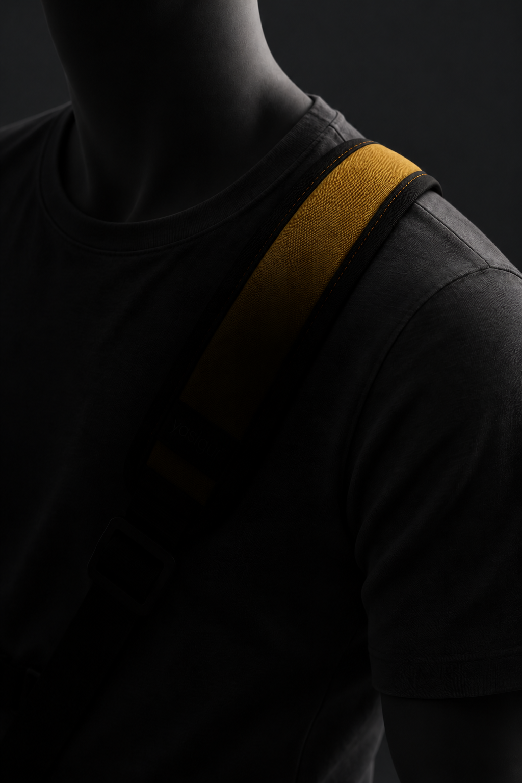 Shadowed three-quarter concept view of the YASIGU sling, with the mustard panel continuing over the mannequin’s left shoulder and the lower pad concealed.